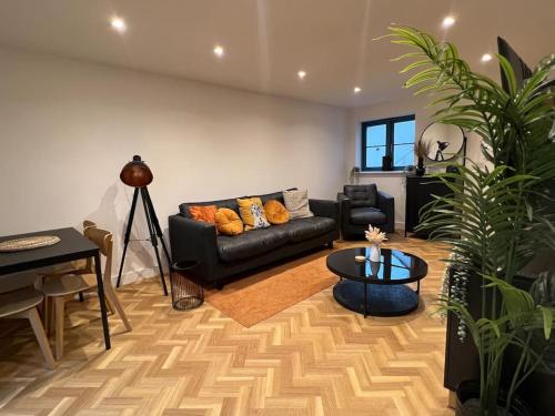 a living room with a black couch and a table at The Orchard - Ground Floor Flat in Bristol
