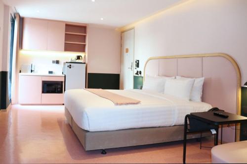 a bedroom with a large white bed and a kitchen at The Quarter Ratchathewi by UHG in Bangkok