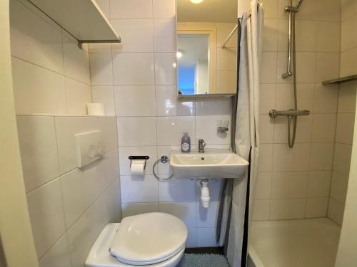een witte badkamer met een toilet en een wastafel bij De Meerval in Katwijk aan Zee