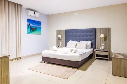 a bedroom with a large bed with a blue headboard at Hotel Fénix in Nampula