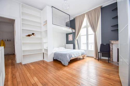 a bedroom with white walls and a bed and a wooden floor at Appt 5 pers au coeur de Dinard classé 2 étoiles in Dinard