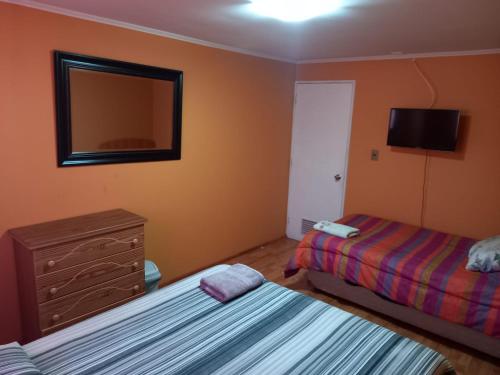 sypialnia z 2 łóżkami, komodą i lustrem w obiekcie HOSTAL LA CASONA ALFREDO CAMPOS w mieście Ovalle