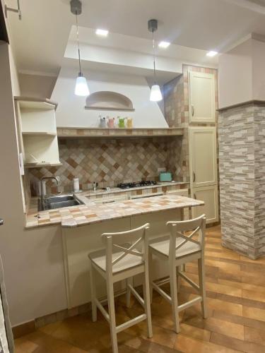 a kitchen with two chairs and a table and a sink at Domus Melius in Castellammare di Stabia
