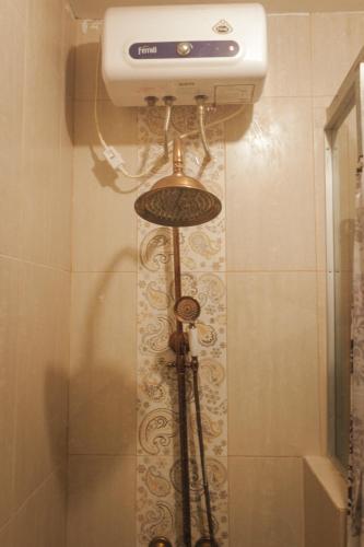 a shower in a bathroom with a tank and a toilet at Cokro Hinggil - Traditional View in Sleman