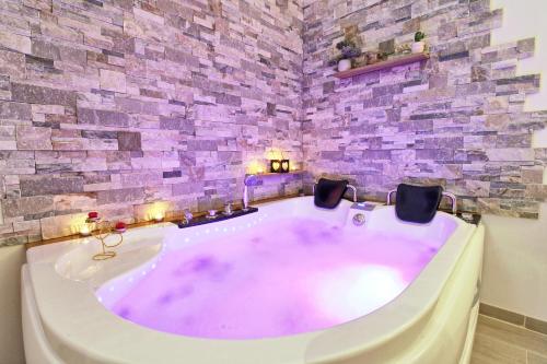 a large bath tub in a room with a stone wall at Aux 3 Glands - Nature & Spa in Dieffenbach-au-Val