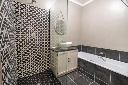 Glenmore Guesthouse في بلومفونتين: حمام مع حوض استحمام ومغسلة