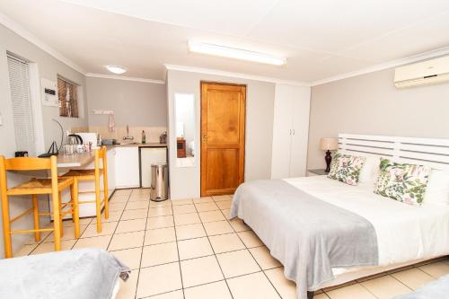 a bedroom with a large bed and a kitchen at Glenmore Guesthouse in Bloemfontein