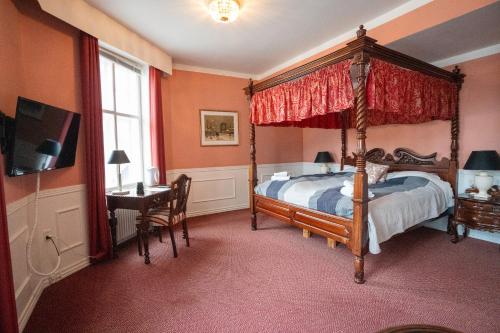 a bedroom with a canopy bed and a desk at Frederiksværk Hotel in Frederiksværk
