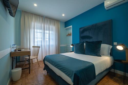 una camera blu con letto, tavolo e scrivania di D'Ávila Peixinho 180 ad Aveiro