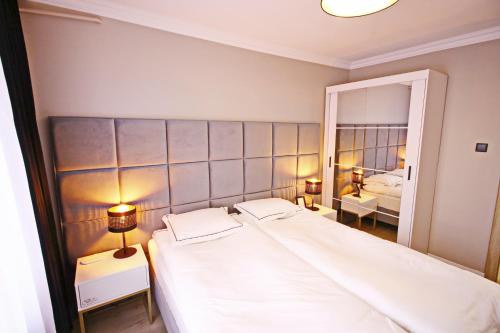 a bedroom with a large white bed and a mirror at Saint Barbara Gorgeous 3 room apartments in the heart of Gdansk in Gdańsk