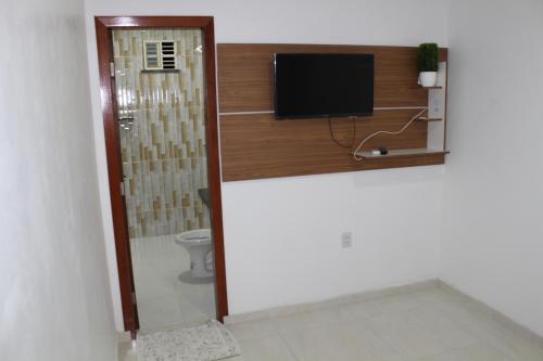 a bathroom with a toilet and a flat screen tv at Hotel Jardim Tropical in Boa Vista