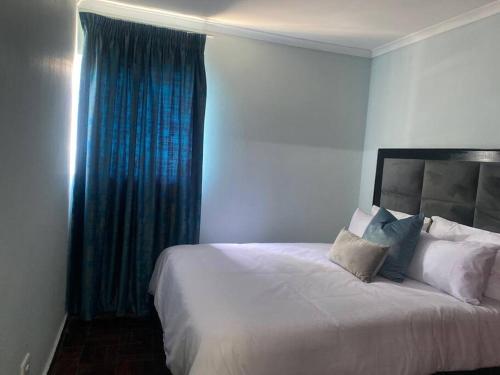 sypialnia z dużym białym łóżkiem z niebieskimi zasłonami w obiekcie The Royal Blue w mieście Sandown