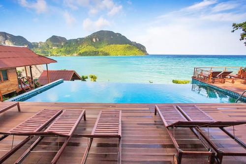 a swimming pool with two chairs and the ocean at The Cobble Beach Hotel- Phi Phi Island in Phi Phi Don