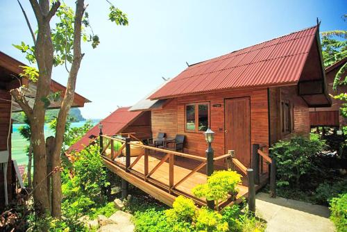 a wooden cabin with a deck and a red roof at The Cobble Beach Hotel- Phi Phi Island in Phi Phi Don