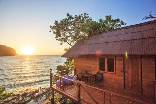 dom na brzegu wody z zachodem słońca w obiekcie The Cobble Beach - SHA Certified Vaccinated w Ko Phi Phi