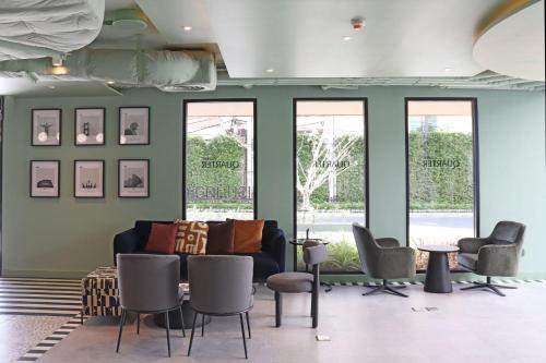 a living room with a couch and chairs and windows at The Quarter Ratchathewi by UHG in Bangkok