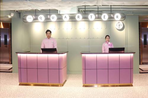 two people standing behind counters in an office at The Quarter Ratchathewi by UHG in Bangkok