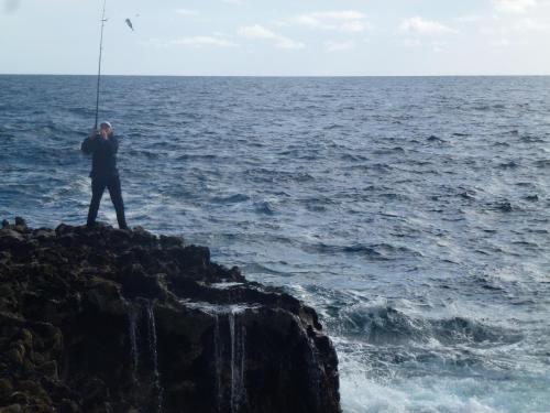 a man is standing on a rock by the ocean at Aran Walkers Lodge in Inis Mor