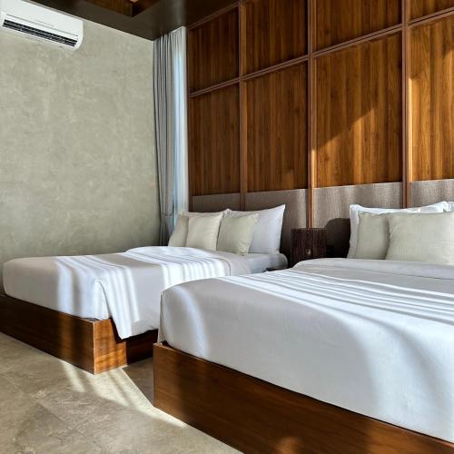 two beds in a hotel room with white sheets at TANA Beach Villas in Lian