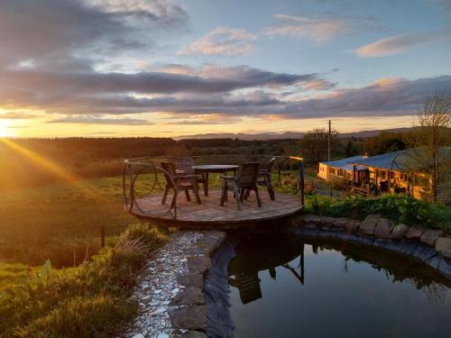 a table and chairs sitting on a wooden platform over a pond at Warriors View in Drumahayre