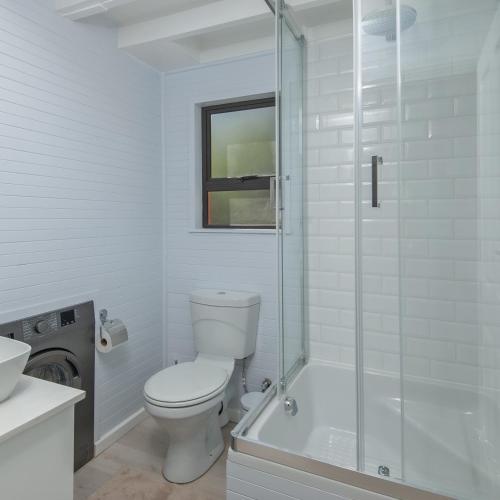 a white bathroom with a toilet and a shower at The Blue Cabin in Fisherhaven