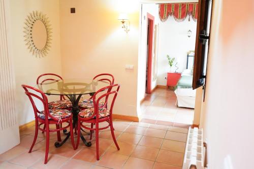 ein Esszimmer mit einem Glastisch und roten Stühlen in der Unterkunft Hotel Rural El Zaguán in Lerma