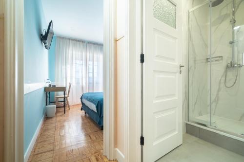 a bathroom with a shower and a bed and a glass door at D'Ávila Peixinho 180 in Aveiro