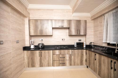 eine Küche mit Holzschränken und einer schwarzen Arbeitsplatte in der Unterkunft Washington Court - Deluxe One Bedroom Apartment in Accra
