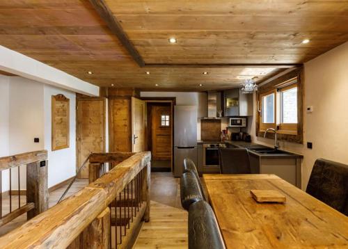 a kitchen with a wooden table and a wooden ceiling at Superbe logement, jacuzzi extérieur, vue, sauna in Champagny-en-Vanoise
