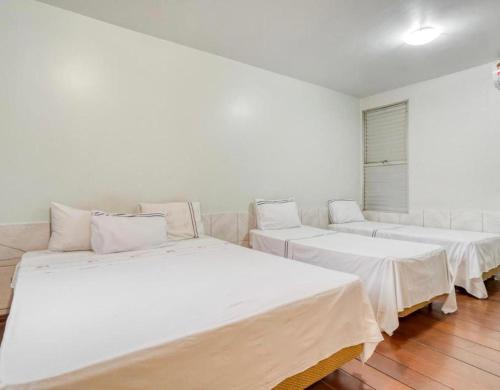 3 camas num quarto com paredes brancas e pisos em madeira em Itajubá Classic Hotel Goiânia em Goiânia