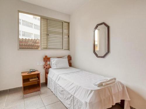 een kleine slaapkamer met een bed en een spiegel bij Itajubá Classic Hotel Goiânia in Goiânia