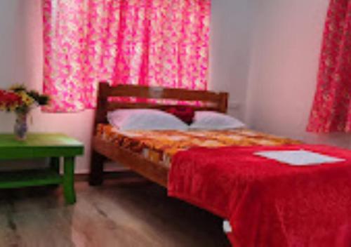 Schlafzimmer mit einem Bett mit einer roten Bettdecke in der Unterkunft Serina House Malvan in Malvan