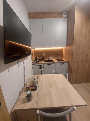 a kitchen with a wooden table and a sink at Apartamenty Jaskółcza in Bydgoszcz