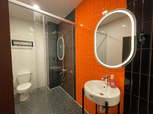 La salle de bains est pourvue d'un lavabo, d'un miroir et de toilettes. dans l'établissement Nhà mình Homestay, à Rạch Giá