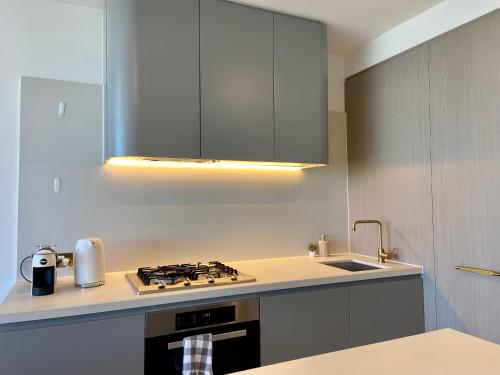 a kitchen with a stove top oven next to a sink at Skygarden Luxury Condo in Glen Waverley