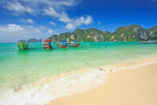 a group of boats sitting in the water on a beach at The Cobble Beach Hotel- Phi Phi Island in Phi Phi Don