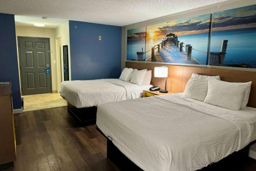 a hotel room with two beds and a painting of a pier at Days Inn by Wyndham Sarasota I-75 in Sarasota