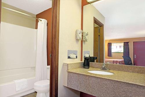 a bathroom with a sink and a toilet and a mirror at Super 8 by Wyndham Cincinnati-Springdale OH in Springdale