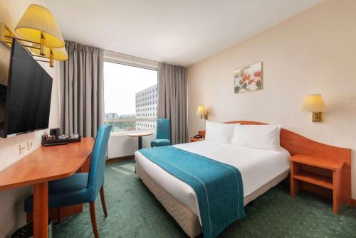 Ramada by Wyndham Bucharest Parc Hotel في بوخارست: غرفة في الفندق بها سرير ومكتب وسرير ومكتب