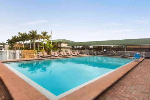 a large swimming pool with chairs and a building at Ramada by Wyndham Sarasota Waterfront in Sarasota
