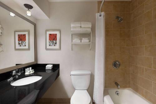 a bathroom with a toilet and a sink and a shower at Ramada by Wyndham Sarasota Waterfront in Sarasota