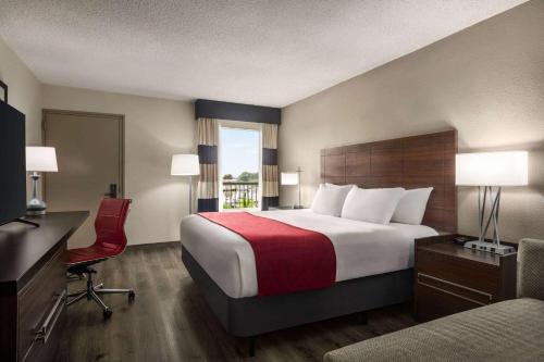a hotel room with a large bed and a red chair at Ramada by Wyndham Sarasota Waterfront in Sarasota
