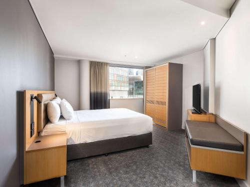 a hotel room with a bed and a flat screen tv at Novotel Sydney Darling Harbour in Sydney