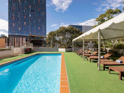 a pool with chairs and umbrellas on a building at Novotel Sydney Darling Harbour in Sydney