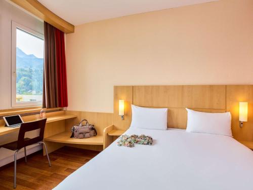 una camera d'albergo con letto, scrivania e finestra di ibis Luzern Kriens a Lucerna