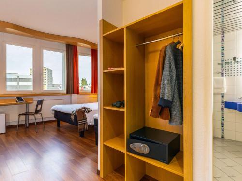 Habitación con armario, cama y escritorio. en ibis Luzern Kriens, en Lucerna