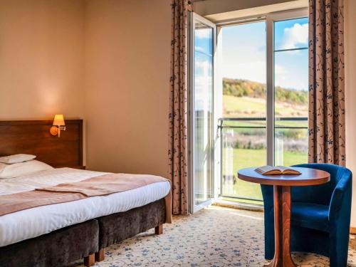 a bedroom with a bed and a table and a window at Mercure Racławice Dosłońce Conference&SPA in Racławice