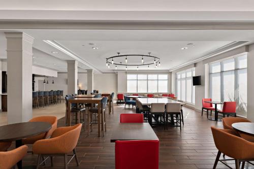 a dining room with tables and chairs and windows at Hilton Garden Inn Omaha East/Council Bluffs in Council Bluffs