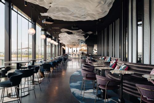 a restaurant with tables and chairs and large windows at DoubleTree by Hilton Amsterdam Centraal Station in Amsterdam