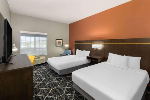 a hotel room with two beds and a flat screen tv at La Quinta by Wyndham Olathe in Olathe